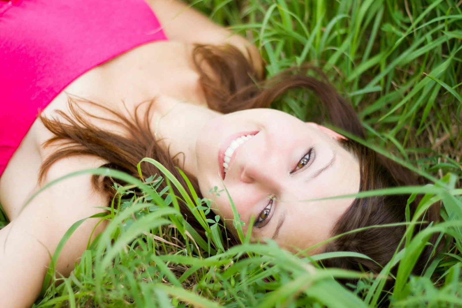 Femme souriante allongée dans l'herbe.